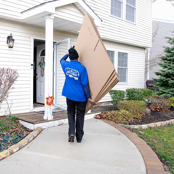 A Gotham mover carrying flattened cartons into a house