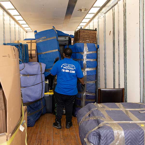 A Gotham mover inside a truck stacking pad-wrapped furniture and boxes