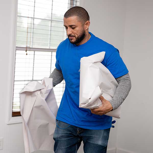 A Gotham mover carrying sheets of packing paper by a window