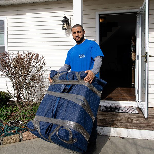 A Gotham mover carrying a pad-wrapped item out of a front door