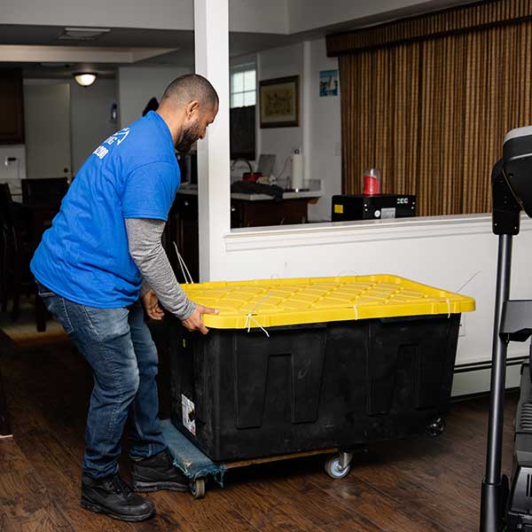 A Gotham mover rolling a large storage tote on a dolly through a kitchen