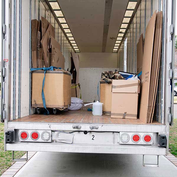 The open rear of a box truck with strapped cartons and flattened boxes inside