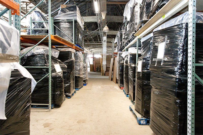 An aisle of steel pallet racking holding shrink-wrapped goods in the warehouse