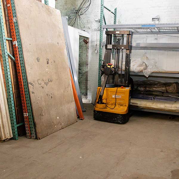 A pallet jack and tall panels against steel racking in the warehouse